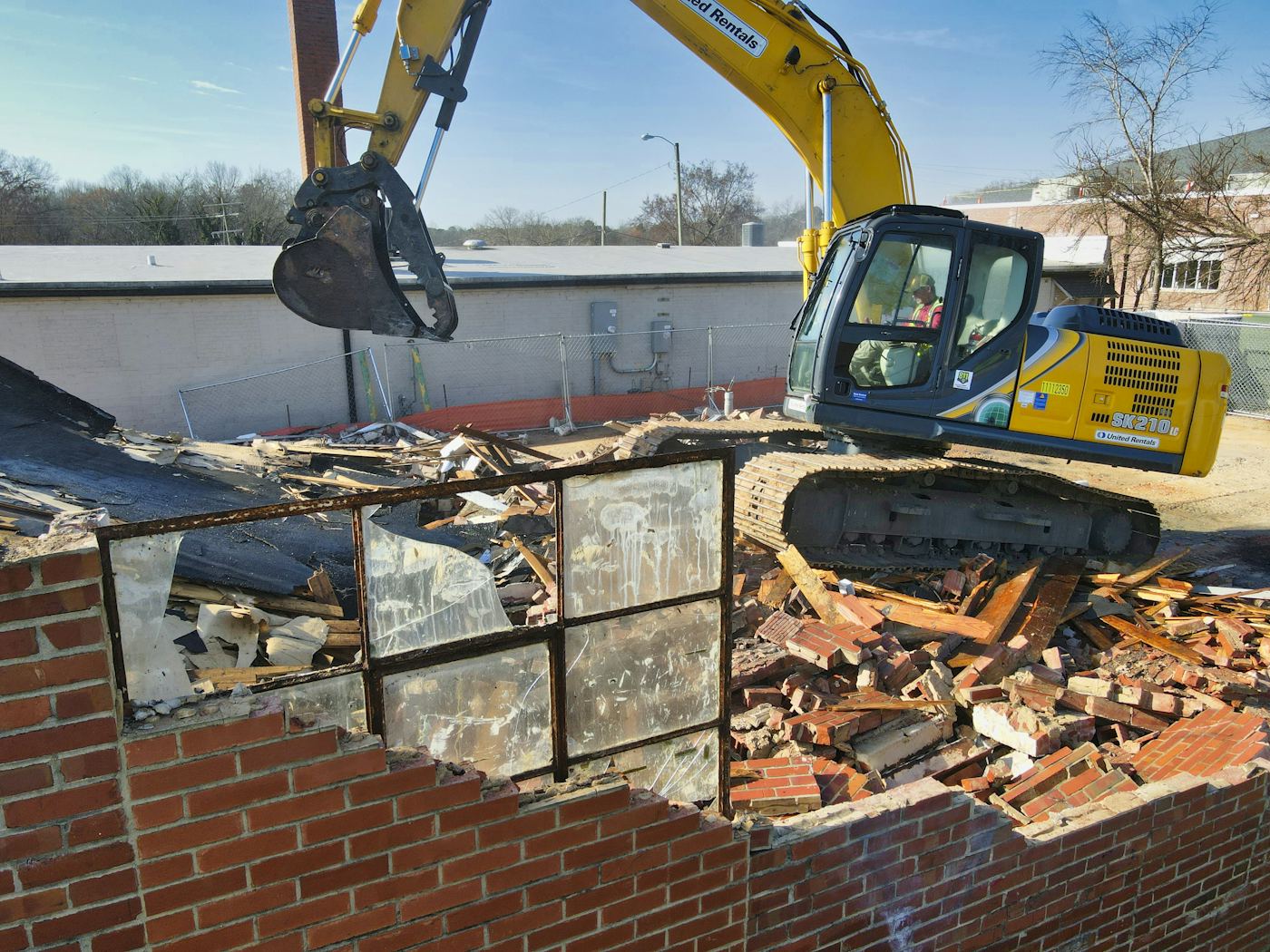Graafmachine bij de selectieve sloop van een gebouw, met gescheiden puin op de voorgrond